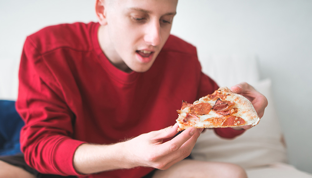 Hungry man holds pepperoni pizza slice